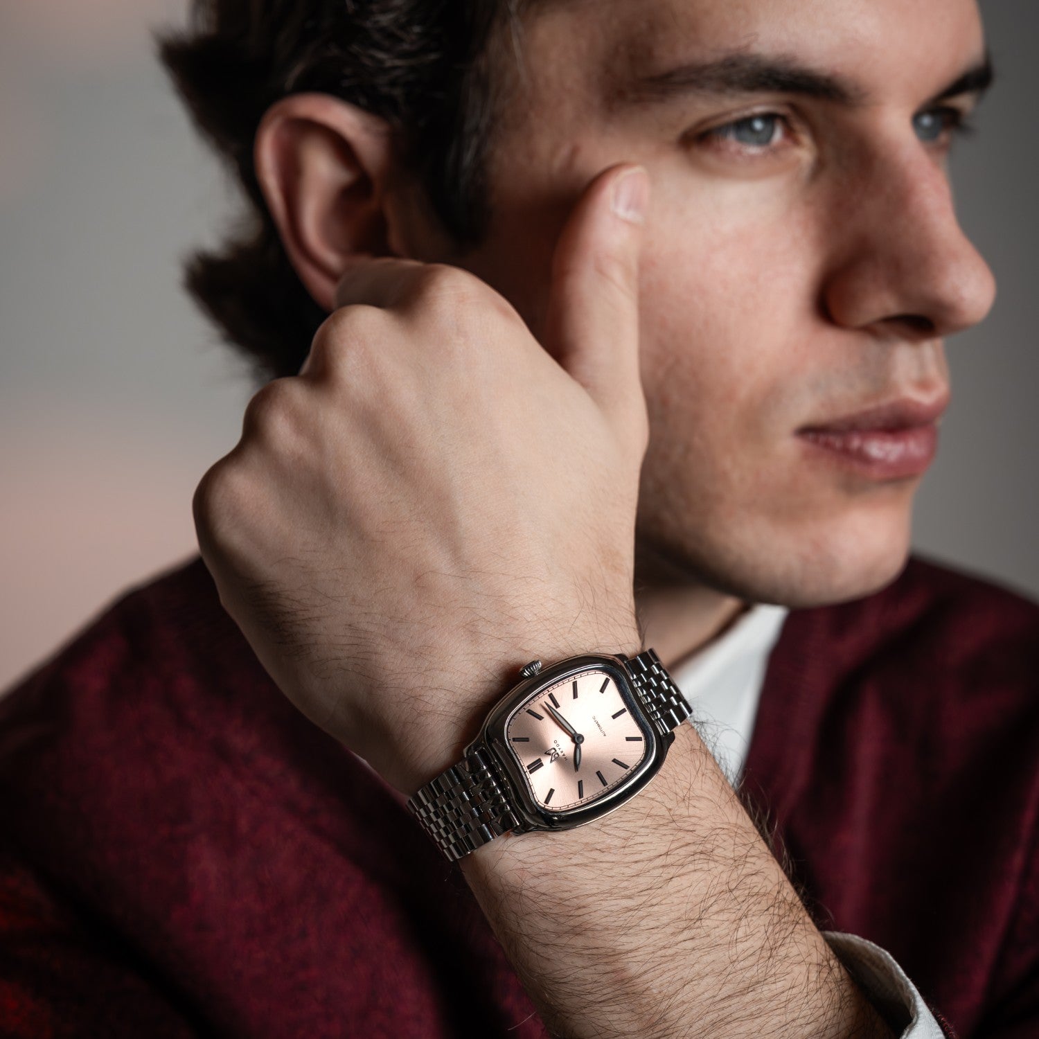 Man wearing a watch with a neutral background