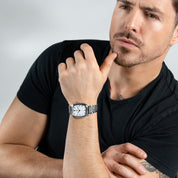 Man wearing a black t-shirt and a watch with a neutral background