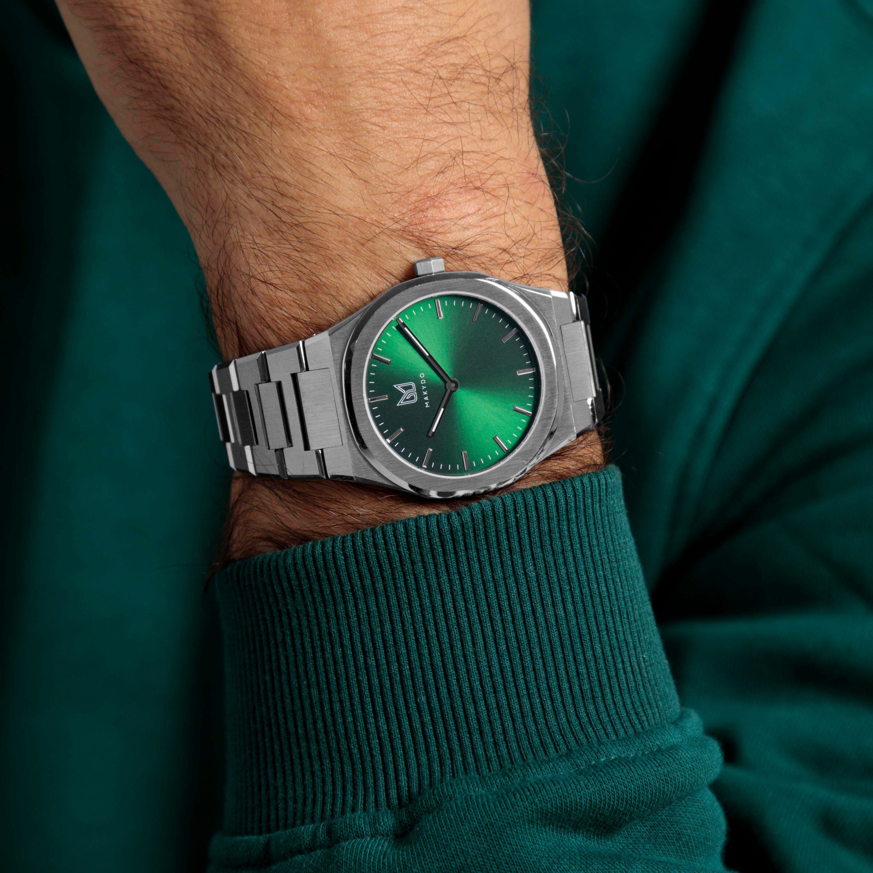 With reminiscent of nature's captivating Emerald, Makydo emerald green men's watch is a symbol of renewal, prosperity, and hope, inspiring us to embrace the endless possibilities. The brilliant, highly transparent sapphire crystal with Anti reflective coating expose the sophisticated silver baton hands with BGW9 Lume. The flawless symmetry of the 316L Stainless Steel integrated bracelet complimented with a 6.7mm of slim case powered by a sturdy Miyota quartz movement.