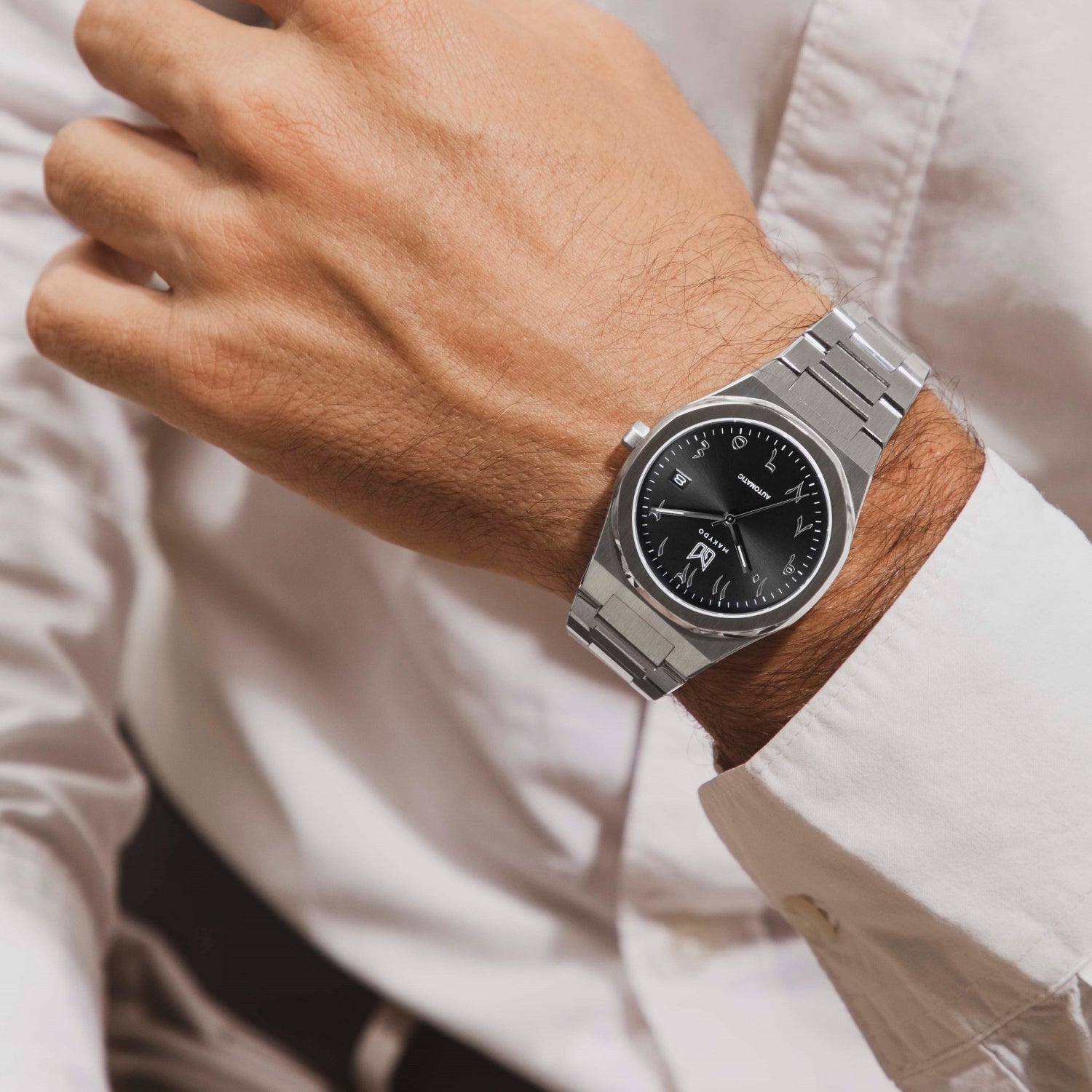 Wrist shot of MAKYDO Onyx Black Middle East 38 automatic unisex watch, featuring a black  sunburst  dial with arabic numerals as indices.  316L Stainless Steel integrated bracelet complimented with a 9mm of slim case powered by a sturdy Japan MIYOTA 9015 movement.